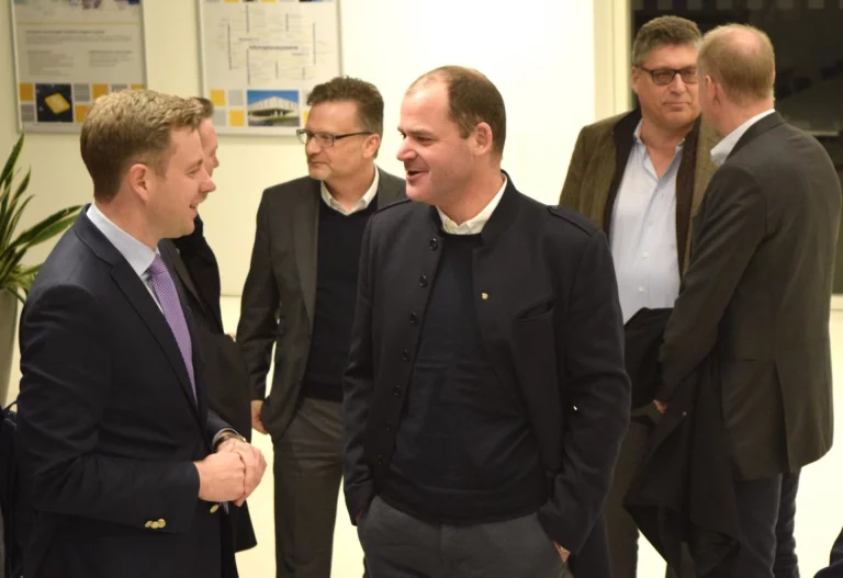 Männer in Geschäftskleidung im Gespräch bei einer Veranstaltung zur Digitalisierung in der Instandhaltung