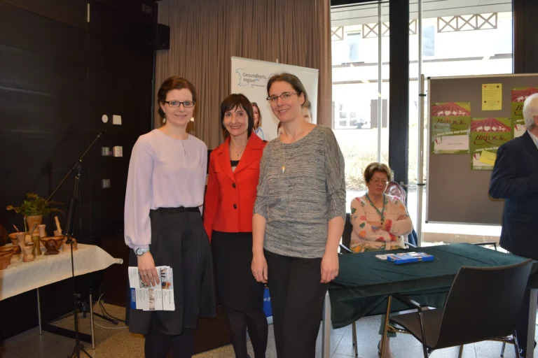 Drei Frauen stehen vor Infowand und Rollup der Gesundheitsregion, im Hintergrund Infostand mit Mörsern