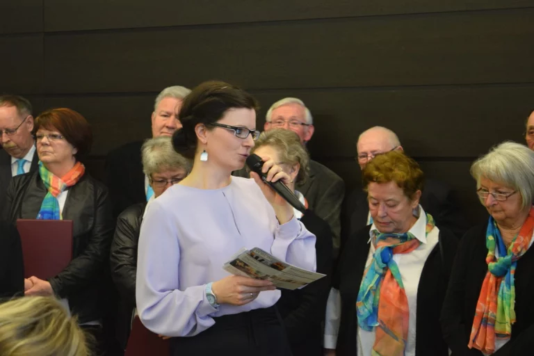 Frau mit Mikrofon spricht vor Publikum beim Aktionstag, im Hintergrund Zuhörende
