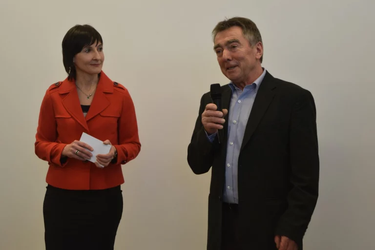 Frau in roter Jacke und Mann mit Mikrofon sprechen beim Aktionstag zu Gästen