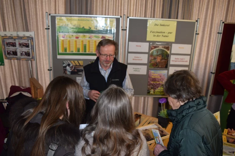 Mann erklärt Imkerei-Infotafeln einer Besuchergruppe am Stand des Aktionstags