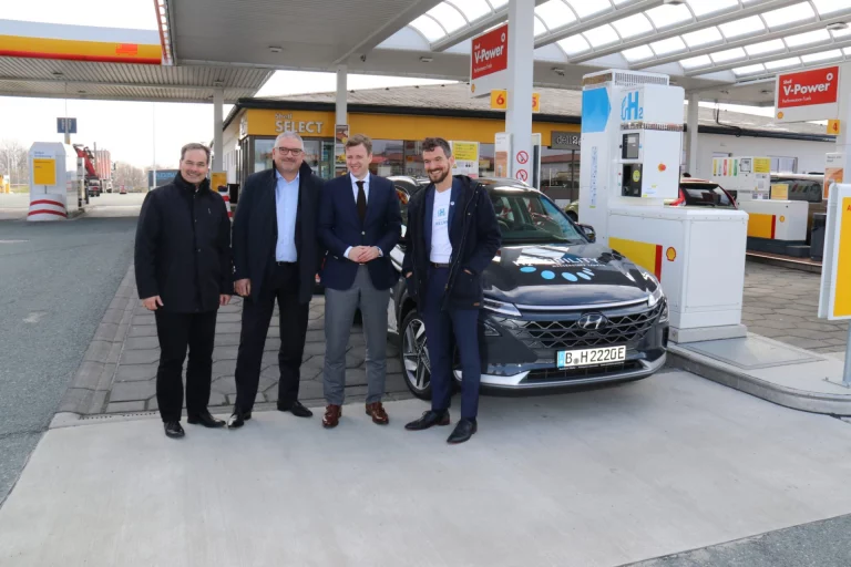 Vier Männer stehen vor einem Hyundai-Wasserstoffauto an der neuen Wasserstofftankstelle Berg