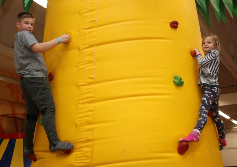 Junge und Mädchen klettern an einer aufblasbaren Kletterwand