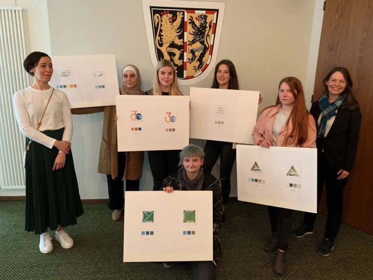 Yasmine Rauh, Lehrerin der Fachoberschule für Produktdesign in Selb (links) und Veronika Brunner, Klimaschutzmanagerin des Landkreises Hof (rechts), gemeinsam mit Schülerinnen der Produktdesignschule und deren Entwürfen.