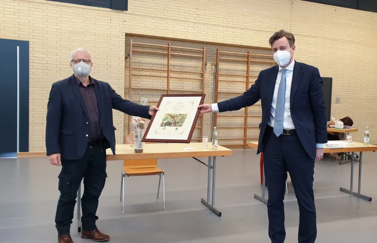 Zweckverbandsvorsitzender Landrat Dr. Oliver Bär (rechts) verabschiedet seinen Stellvertreter Jürgen Hauck. Als Geschenk überreichte er ein originales Dokument namens „Aufbruch“. Das Dokument wurde in limitierter Form aufgelegt und erstmals am 17. Juni 1990 in Mödlareuth ausgegeben.