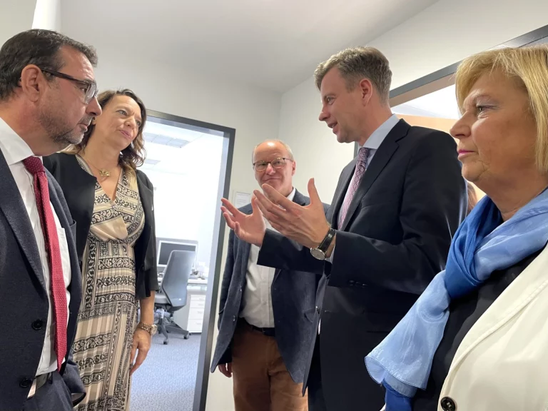 Gruppe von Personen im Gespräch in einem Büroflur bei einem Besuch der Pflege-Leitstelle