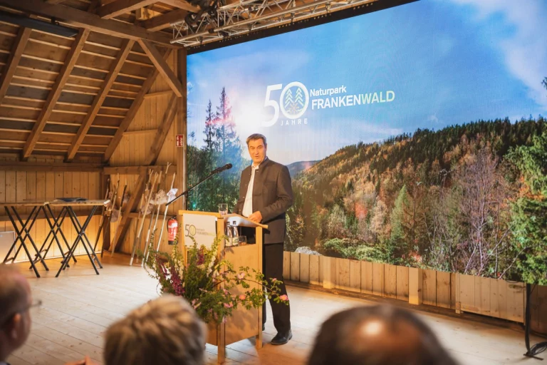 Markus Söder spricht am Rednerpult vor Leinwand mit Schriftzug „50 Jahre Naturpark Frankenwald“