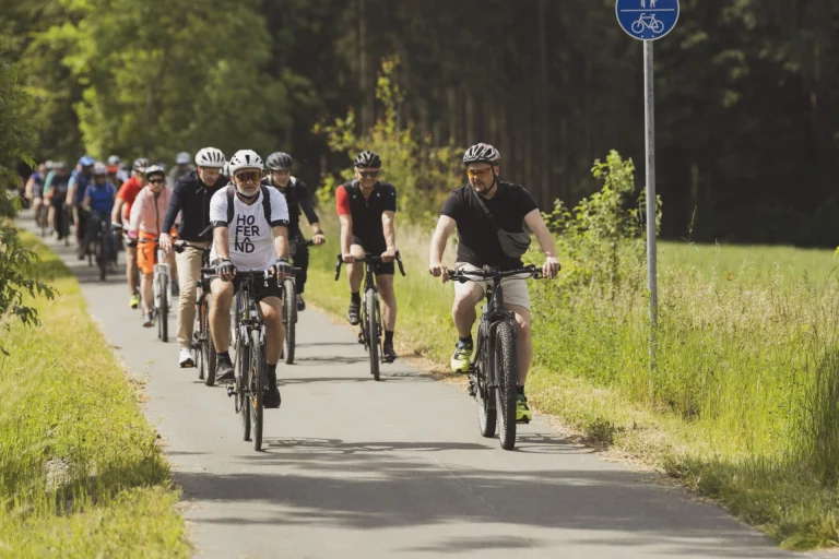 Radfahrgruppe auf asphaltiertem Saaleradweg zwischen Wald und Wiese