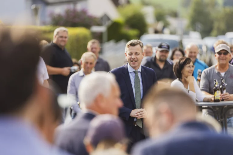 Mann im Anzug inmitten einer Menschengruppe bei einer Feier im Freien