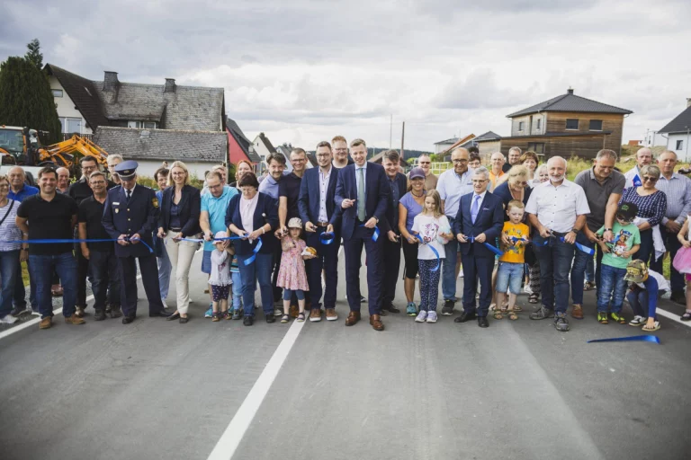 Menschengruppe durchschneidet blaues Band zur Eröffnung der neuen Kreisstraße