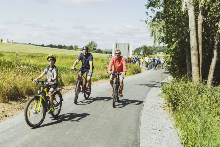 Erwachsene und Kind mit Fahrrädern und Helmen auf dem Saaleradweg zwischen Feldern