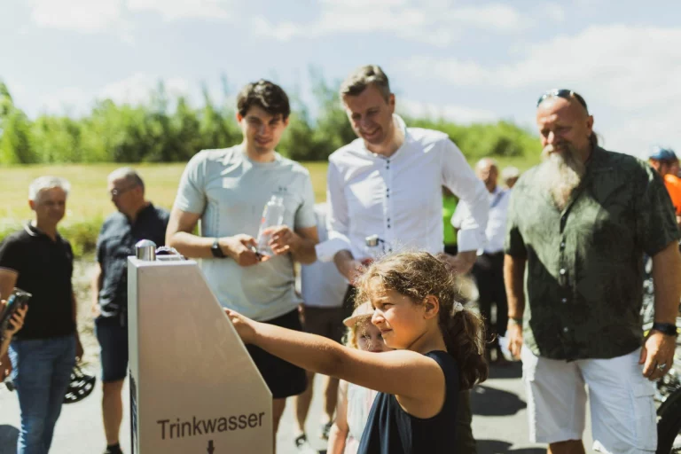 Trinkwasserstation am Saaleradweg wird von Kind und Erwachsenen bei einem Termin im Freien genutzt