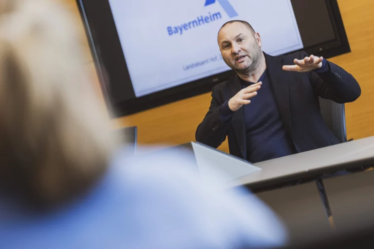 Mann am Konferenztisch erläutert BayernHeim-Präsentation im Landratsamt Hof