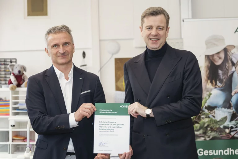 Zwei Männer präsentieren Förderurkunde „Gesunde Kommune“ der AOK Bayern