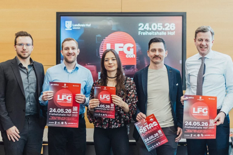 Fünf Personen präsentieren Plakate zur LFG Con 2026 vor einem Bildschirm mit Veranstaltungsdatum