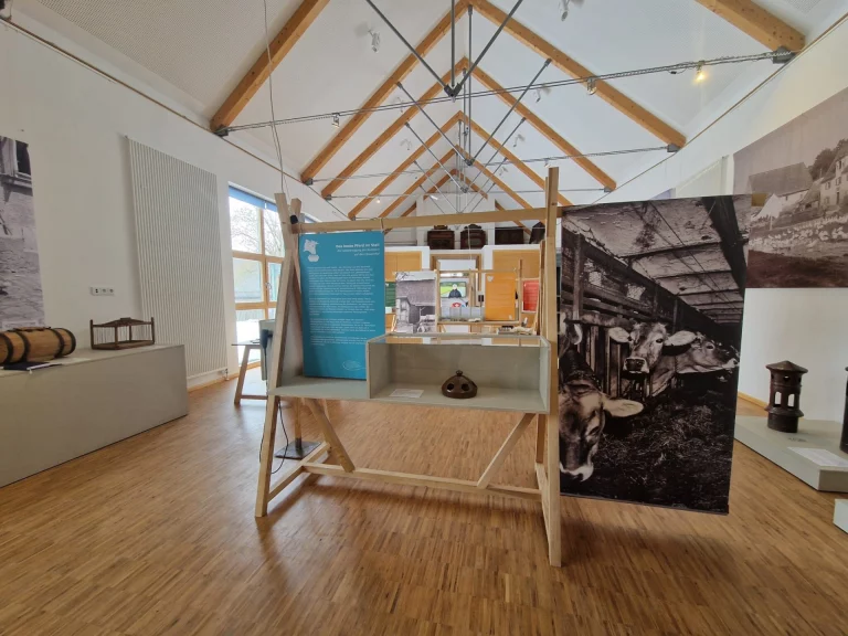 Museumsraum mit historischen Fotografien, Stellwänden und Vitrine zu bäuerlichem Alltag