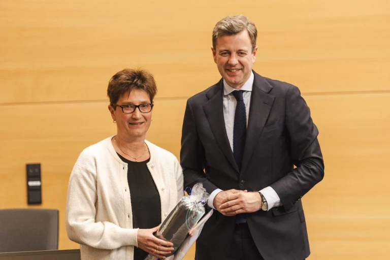 Frau überreicht Landrat ein verpacktes Geschenk bei einer Ehrung