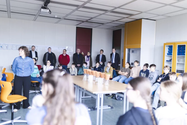 Schulklasse und Erwachsene im Klassenzimmer bei einer Vorführung zu Pflanzen und Klimawandel