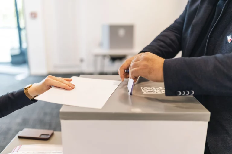 Person steckt Stimmzettel in eine Wahlurne bei der Kreistagswahl