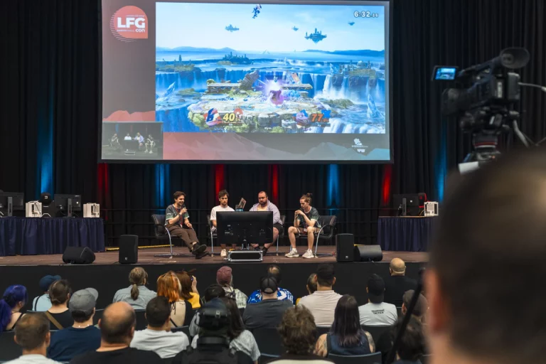 Podiumsgespräch mit vier Teilnehmern vor Leinwand mit Spielszene und LFG-Con-Logo