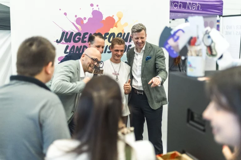 Jugendliche und Erwachsene lachen gemeinsam vor dem Banner Jugendforum Landkreis Hof