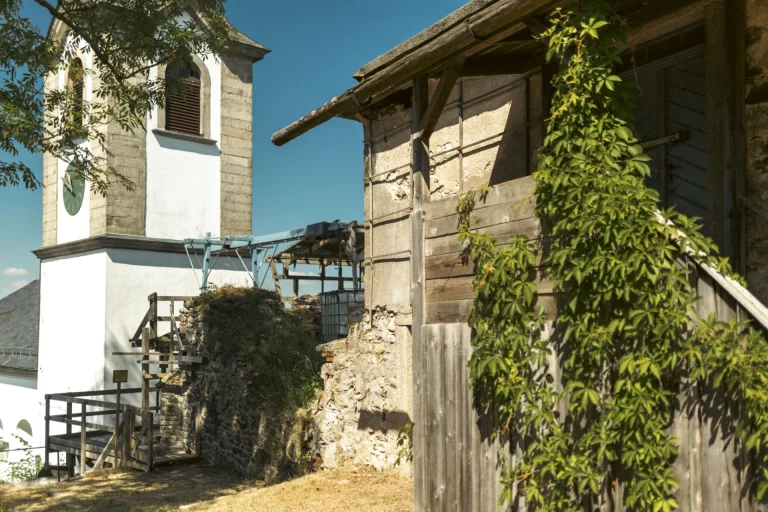 Kirchturm und renoviertes Fachwerk-Nebengebäude mit Wein bewachsen im Dorfkern von Hallerstein